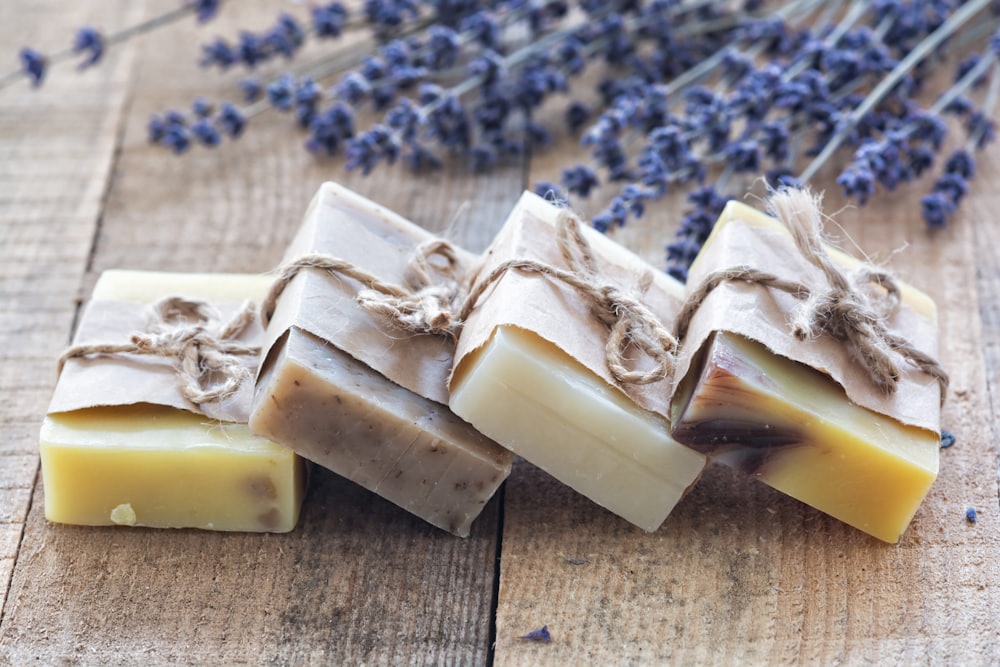 Handmade soap bars arranged on wood beside dried lavender